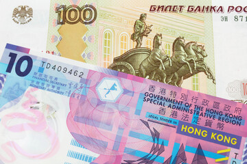 A macro image of a Russian one hundred ruble note paired up with a pink and purple, plastic ten dollar bill from Hong Kong.  Shot close up in macro.