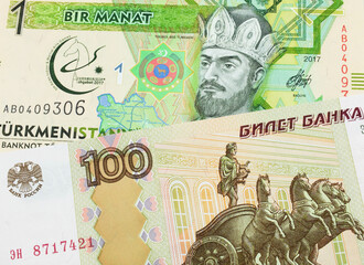 A macro image of a Russian one hundred ruble note paired up with a green and yellow one manat note from Turkmenistan.  Shot close up in macro.