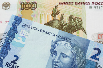 A macro image of a Russian one hundred ruble note paired up with a blue two real bank note from Brazil.  Shot close up in macro.