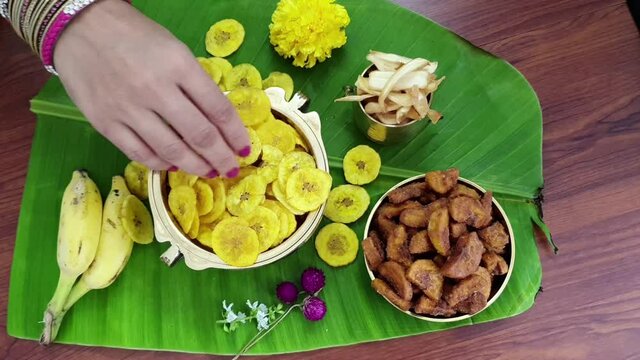 Video of banana chips traditional Kerala fried snack  for Indian lunch Onam sadhya, on banana leaf with  hot curries ,sweet dessert for harvest festival in India. woman hand taking chips.