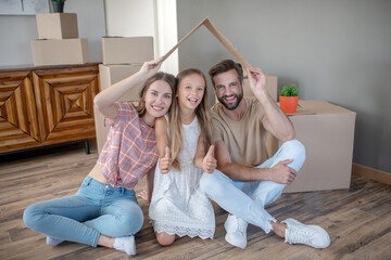 Family sitting under paper roof and smiling