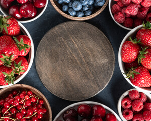 Berries frame with strawberries, raspberries, blueberries, cherries, currants on dark stone background. Flat lay, top view, place for text 