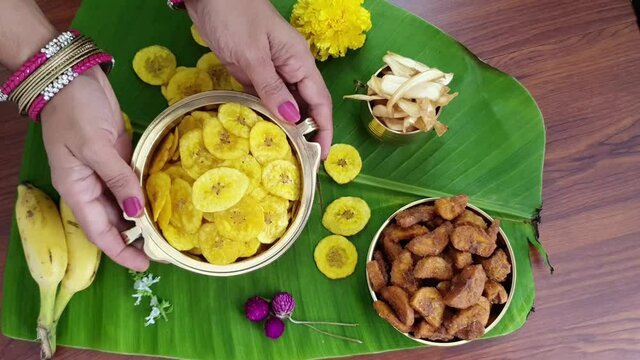 Video of banana chips traditional Kerala fried snack  for Indian lunch Onam sadhya, on banana leaf with  hot curries ,sweet dessert for harvest festival in India. woman hand taking chips.