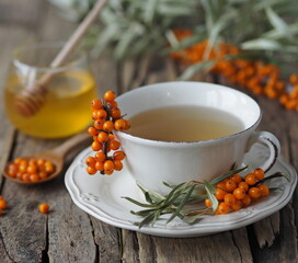 Sea buckthorn branches with berries, tea, honey and sea buckthorn jam on a wooden background. The season for harvesting medicinal sea buckthorn.