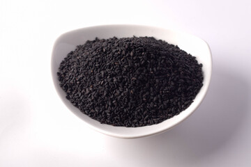 Black sesame seeds in white ceramic cup on a white background
