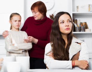 Portrait of young mother upset after quarrel with little daughter standing behind with grandma