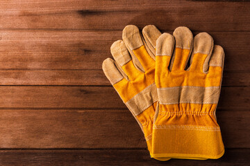 Close up of yellow safety protective gloves on wooden background