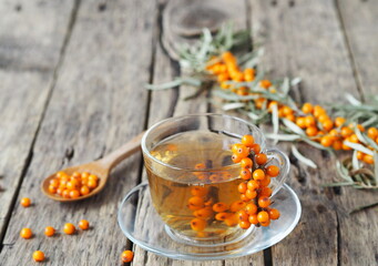 Sea buckthorn branches with berries, tea, honey and sea buckthorn jam on a wooden background. The season for harvesting medicinal sea buckthorn.