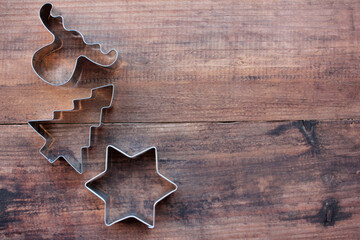 Christmas tree, star, and deer shaped cookie cutters on a wooden table. Christmas background. Top view, copy space
