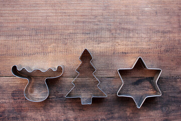 Christmas tree, star, and deer shaped cookie cutters on a wooden table. Christmas background. Top view, copy space
