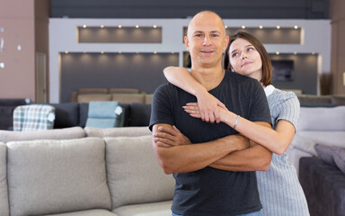 Portrait of happy couple posing in furniture salon shopping room