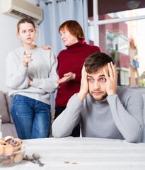 Young upset man during quarrel with wife and her mother at home