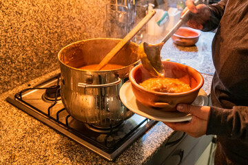 woman serving locro, typical Argentine food on handmade ceramic plates.