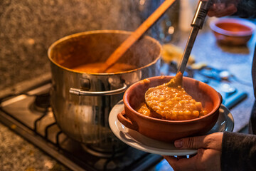 woman serving locro, typical Argentine food on handmade ceramic plates.