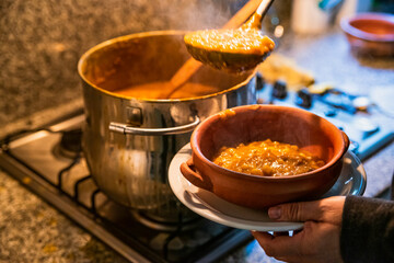 woman serving locro, typical Argentine food on handmade ceramic plates.