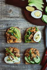 various morning vegetarian toast set with mushrooms, avocado, arugula, cucumber, micro green and eggs. Healthy food on rustic wooden background
