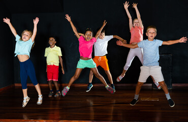 Positive children jumping while studying modern style dance in the class in the evening
