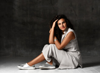 Charming woman in stylish wide leg capri cropped pants, sleeveless jacket and silver shoes sits on the floor