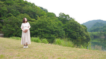草はらを歩く若い妊婦さん