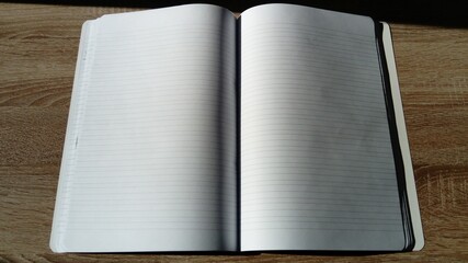 U-turn notebook with blank white pages. Harsh natural sunlight