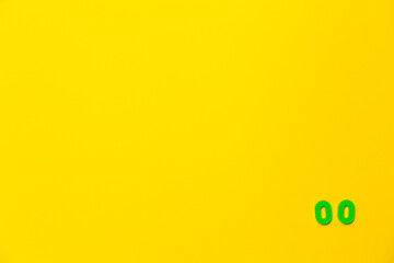 A green plastic toy number zero is located in the lower right corner on a yellow background