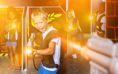 Obraz na płótnie Canvas Emotional teen boy with laser pistol playing laser tag with friends on dark labyrinth. High quality photo