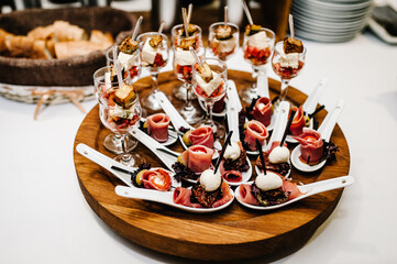 Gourmet appetizers on plastic spoons, variety of mini appetizer with different toppings on plate. Front view above.