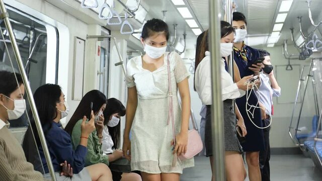 Group of Asian passenger getting off metro subway train at night for transportation with everyone wearing facial mask for pollution and protection from coronavirus in new normal and social distancing 