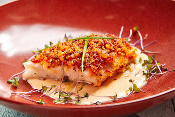 Cod piece with sauce in red deep plate