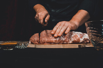 A large piece of raw pork, the cook cuts the pork neck in half.