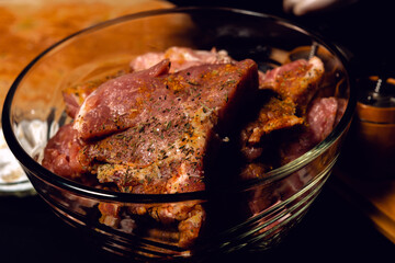 The chef in white gloves rubs pieces of pork with spices, uses curry, basil and salt, marinates the meat on a barbecue.