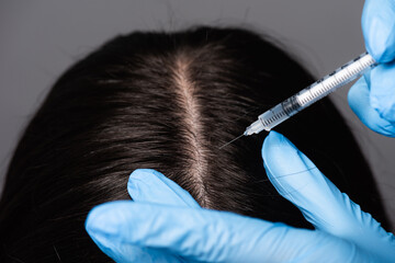 close up view of brunette woman having scalp mesotherapy isolated on black