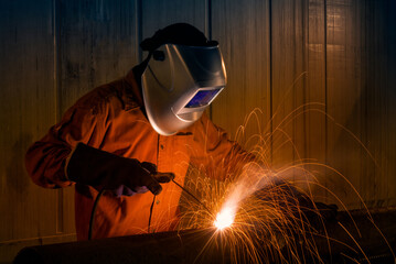 Industrial Worker with safety equipments and protective mask welding steel structure in...