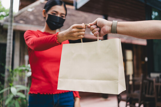 Lady recieving food ingredients from food delivery man with wearing surgical mask for virus preventive, new normal concept.