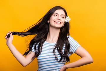 brunette young woman with flowers in hair smiling isolated on yellow