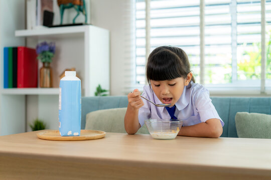 Asian Elementary School Student Girl In Uniform Eating Breakfast Cereals With Milk In Morning School Routine For Day In Life Getting Ready For School.