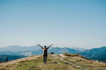 Hiker with backpack relaxing on top of a mountain. Woman enjoying the sunrise.