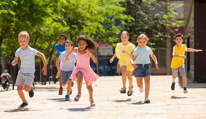 Team of positive kids running in race in the street and laughing outdoors