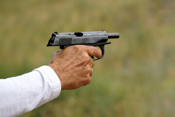   Man's hand with a white sleeve and with a gun.
