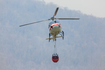 Firefighting  helicopter carrying  water bucket for .extinguish forest fire ,  comeback at lake to filling water © toa555