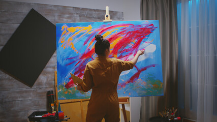Successful young woman creating a masterpiece painting.
