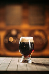 Dark beer in a glass on the wooden table in a bar
