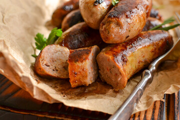 Grilled sausages. Bavarian sausages with herbs and rosemary. Food on parchment. Close-up. Gray background.