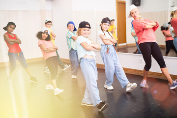 Group of children in casual clothes training hip-hop in class, learning modern dance movements