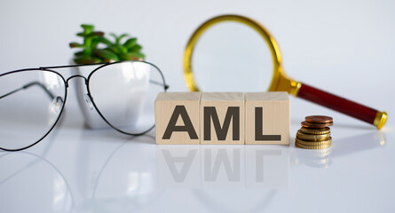 wooden word block AML on white background with glasses and magnifier