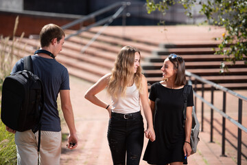 A couple of lesbian students walking together holding hands while a surprised sceptic boy is looking at them.