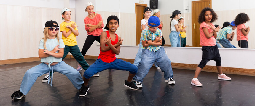 Cheerful preteen girls and boys hip hop dancers doing dance workout with female trainer during group class © JackF