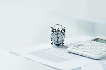 Alarm clock with calculator on financial paperwork on office desk. Finance and business. Deadline and application or reporting window concept. Copy space