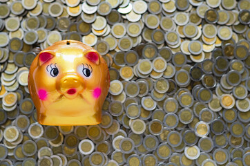 Piggy bank on blurred background of Thai baht coins. Money saving concept.