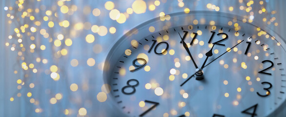 holidays and new year celebration concept - wall clock showing almost midnight with golden...